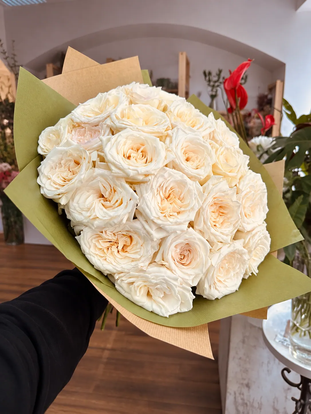 Handgebundener Strauß aus cremefarbenen Rosen, in Papier gewickelt